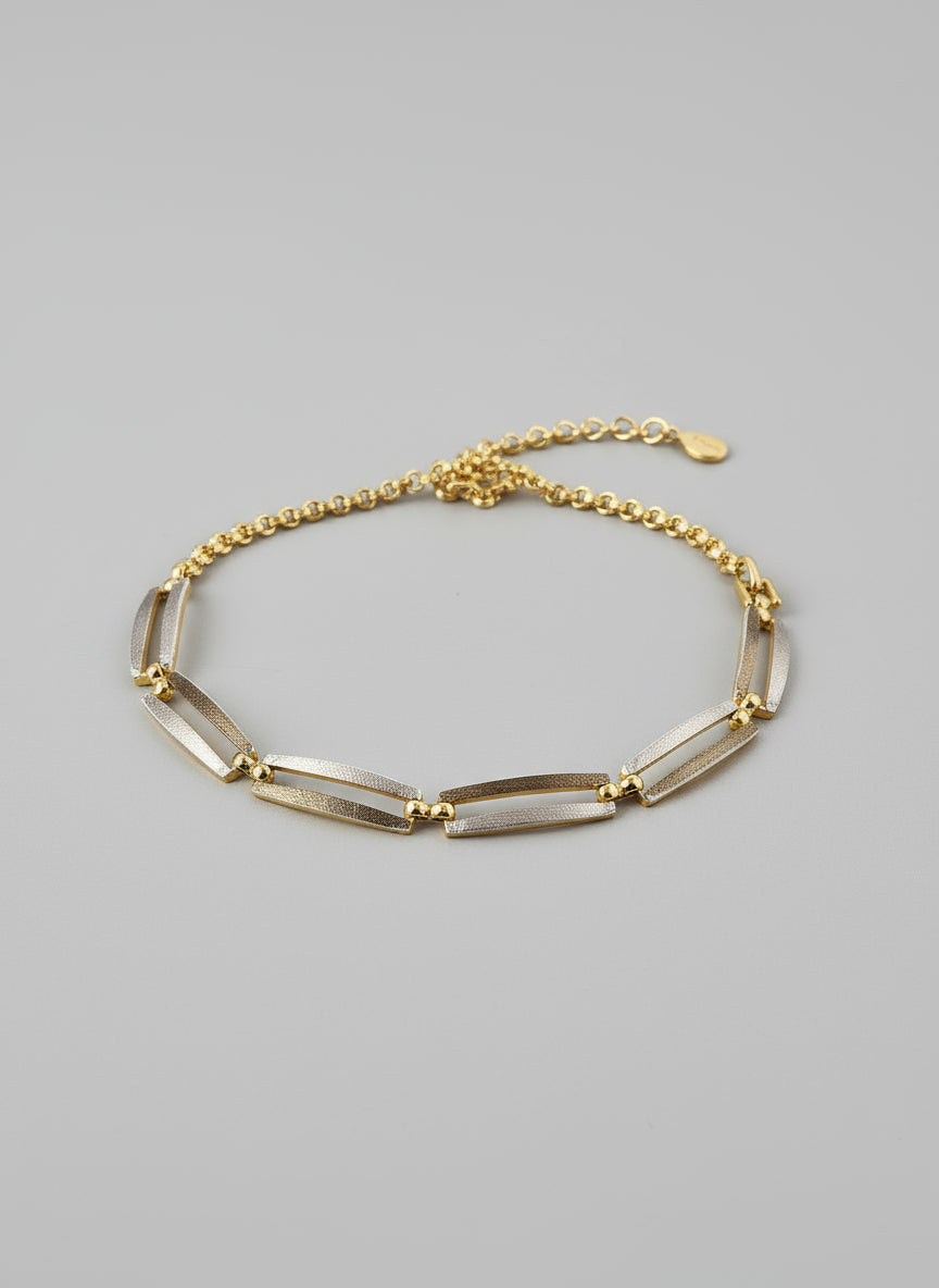Gold bracelet on a textured surface with a blurred background